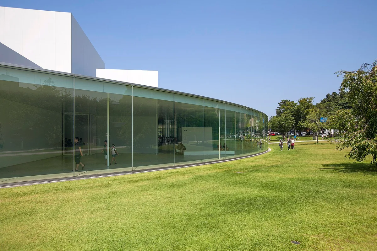 Curved glass exterior of the 21st Century Museum of Contemporary Art, Kanazawa beside a lawn