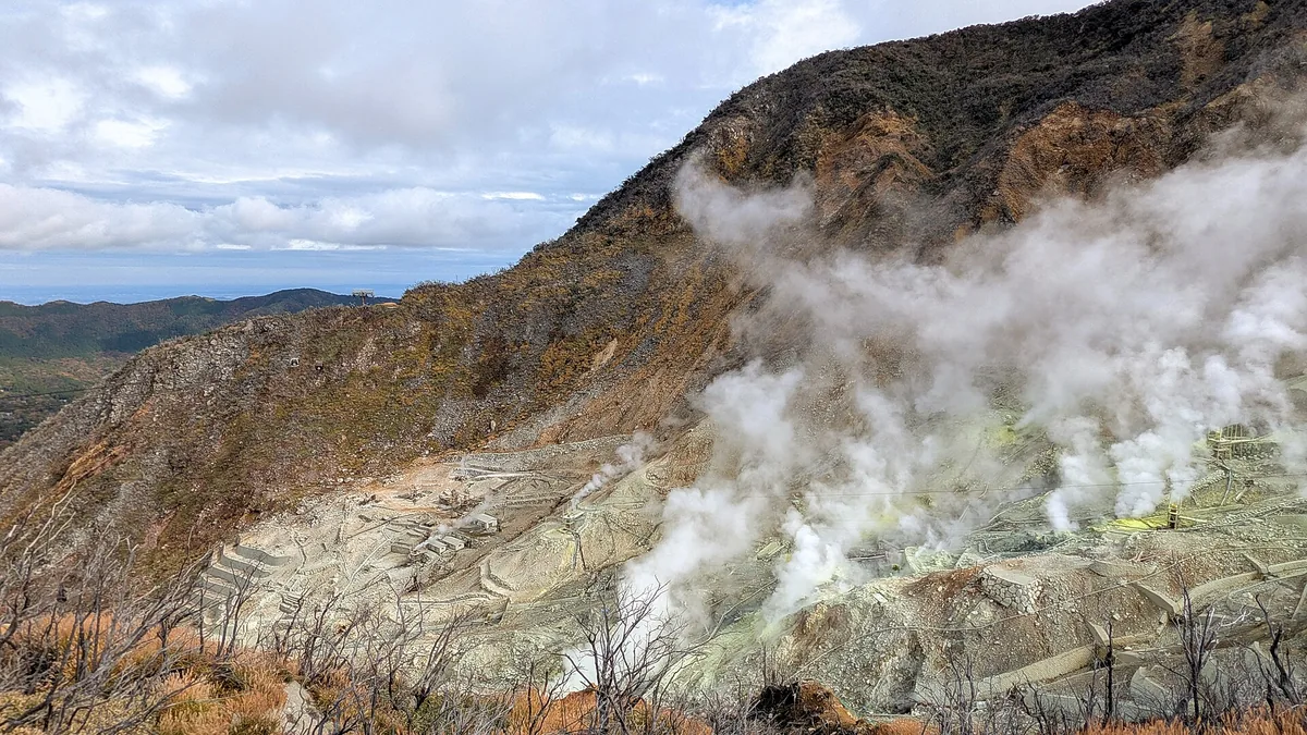 Wide view over Owakudani's volcanic valley, sulphur vents and visitor infrastructure
