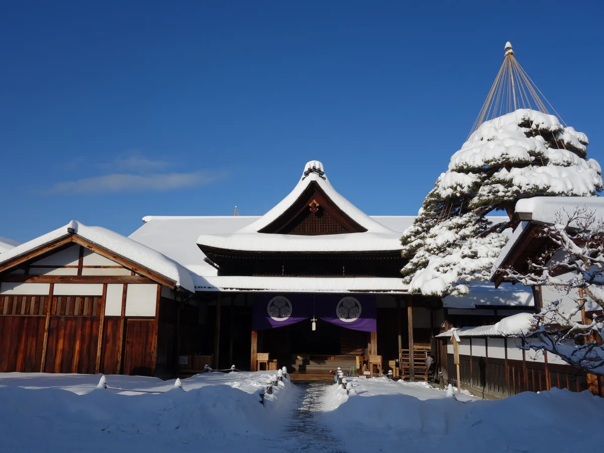 Snow-covered main frontage of Takayama Jinya under a clear winter sky